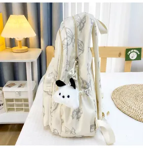Detalle de la mochila blanco roto con estampados de mariposas grises y colgante de perrito