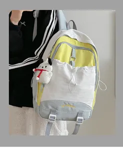 Detail eines Farbblock-Schulrucksacks mit Stickerei und weißem Plüschtier-Anhänger