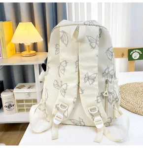 Detalle de mochila crema con patrones de mariposas grises y bolsillo trasero antirrobo