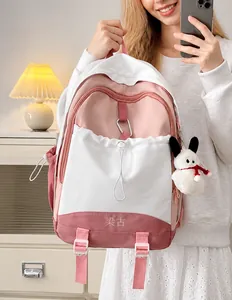 Detail eines pink-weißen Patchwork-Rucksacks mit Plüschanhänger und Kordelzugtasche