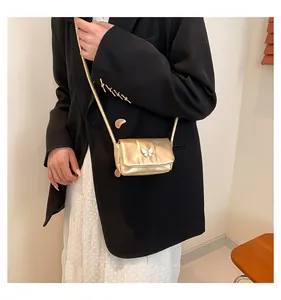 Detail of a mini gold crossbody bag featuring a white butterfly ornament on the flap