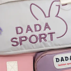 Close-up of DADA SPORT embroidery and pastel color-block fabric on a school backpack