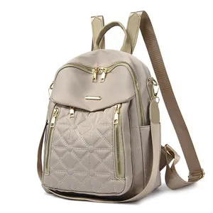 Dettaglio dello zaino in nylon beige con trapuntatura a rombi e cerniere dorate