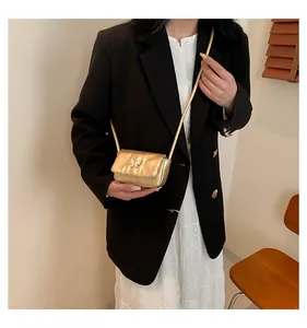 Detail of a gold mini crossbody bag featuring a white bow buckle and fine chain strap