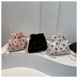 Detailed view of drawstring cord and strawberry pattern on colorful corduroy mini bags