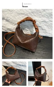 Detail of a brown woven leather handbag with a scrunchie style handle and gold zipper