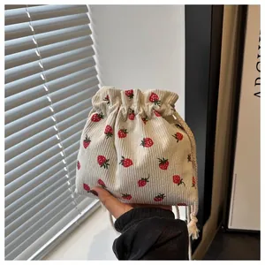 Detail of strawberry printed corduroy bucket bag with drawstring closure and soft texture