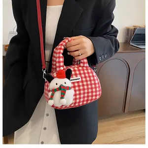 Détail du sac à main à carreaux rouge et blanc avec une peluche sur un tailleur