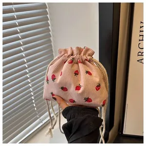 Close-up of pink corduroy drawstring bucket bag with cute red strawberry patterns
