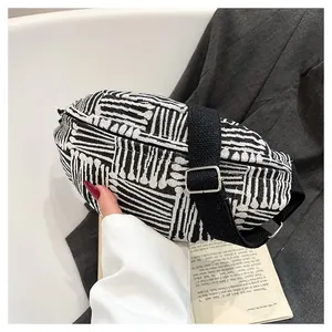 Close-up of black and white striped woven chest bag with adjustable fabric strap