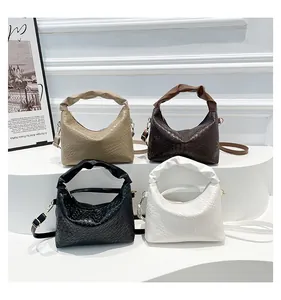 Multiple woven shoulder bags in beige, brown, black and white on a clean white display stand