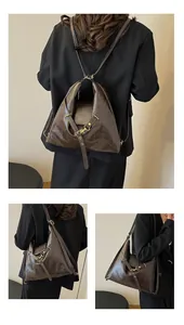 Detalle de mochila grande de cuero marrón oscuro con hebillas doradas y textura de cera
