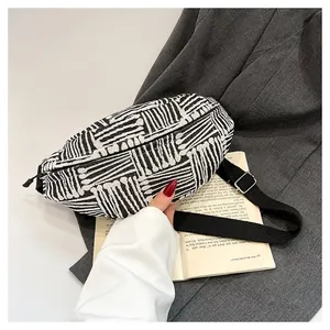Close-up of black and white geometric woven chest bag with adjustable strap and silver buckle