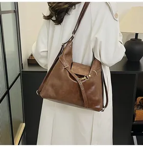 Detalle del bolso tote retro de cuero marrón usado con una gabardina blanca clásica