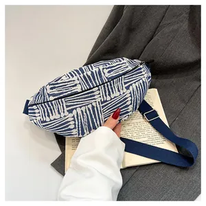 Detail of canvas chest bag with blue stripes on a grey blazer and book background