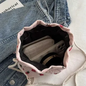 Pink corduroy strawberry drawstring bag showing interior capacity with phone and wallet