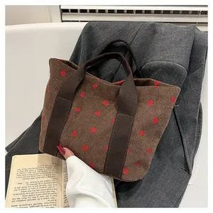 Detail of coffee corduroy tote bag with strawberry print on grey blazer background