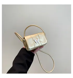 Close-up of golden metallic mini crossbody bag with a white butterfly accent and handle