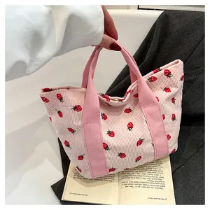 Detail of pink corduroy tote bag with strawberry prints and metal magnetic closure