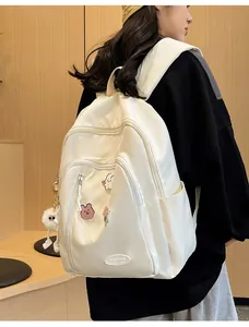Détail du sac à dos de voyage blanc cassé avec badges de dessins animés et pendentif