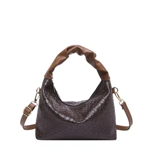 Deep brown woven crescent shoulder bag with pleated handle and gold hardware detail