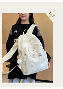 Vue détaillée du sac à dos en nylon blanc avec écussons de dessins animés et pompon