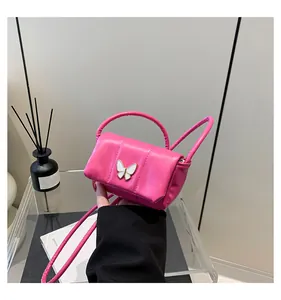 Detail view of mini rose pink quilted bag with white butterfly buckle and crossbody strap