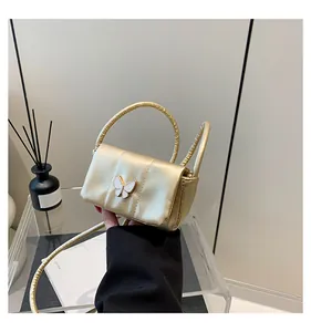 Detail of champagne gold mini crossbody bag with enamel butterfly and quilted side