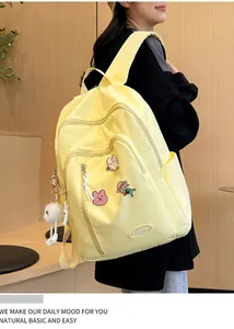 Détail d'un sac à dos jaune avec des épingles mignonnes et un porte-clé en peluche
