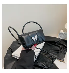 Detail of black quilted shoulder bag featuring a decorative butterfly metal clasp