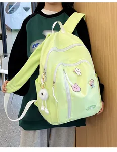 Détail d'un sac à dos en nylon vert pâle avec des badges de dessins animés et un pendentif