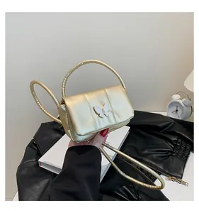 Detail of champagne gold mini crossbody bag featuring a delicate white butterfly ornament