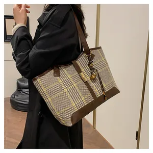 Detail of checkered woolen tote bag with leather trim and gold buckle decoration