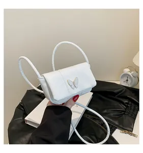 Detail of white PU leather crossbody bag featuring butterfly buckle and dual round handles