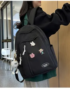 Vue latérale du sac à dos de voyage noir avec charms en peluche et écussons mignons