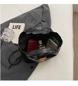 Draufsicht auf das geräumige Innere der schwarzen Lackledertasche mit goldenem Logo-Detail