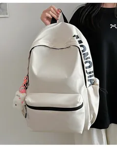Detailopname van witte minimalistische rugzak met grote zwarte letters en een berenhanger