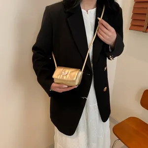 Chic gold mini crossbody bag with butterfly detail on a quilted flap surface