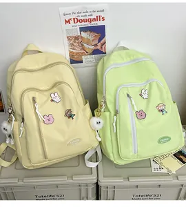 Détail de sacs à dos jaune clair et vert menthe avec badges et breloques pompon