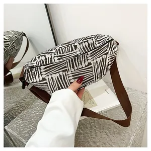 Detail of coffee and white striped canvas chest bag with adjustable shoulder strap