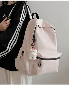 Detail van roze schoolrugzak met trekkoordzakken aan de zijkant en pluchen beer hanger