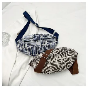 Detail of canvas belt bags featuring ethnic geometric stripes and metal strap buckles