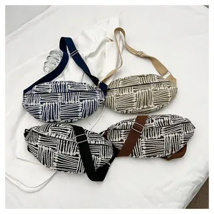 Flat lay of four colorful canvas waist bags with geometric ethnic patterns and adjustable straps