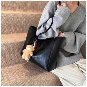 Detail of a black large-capacity tote bag with bear charm and scarf on a model