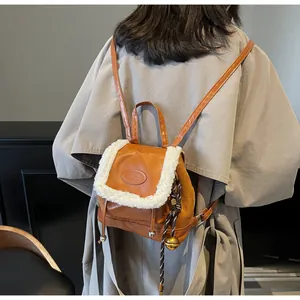 Detail of vintage brown leather backpack featuring fluffy faux shearling trim and bell charm