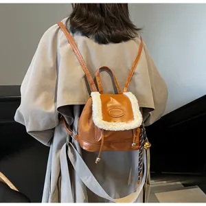 Detail eines braunen Wildleder-Rucksacks mit weißem Plüschbesatz und modischem Patch