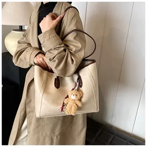 Detail of soft leather tote bag with brown contrast trim and plush bear charm decoration