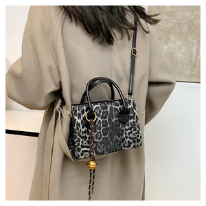 Detail of leopard print crossbody bag featuring gold charm and adjustable strap