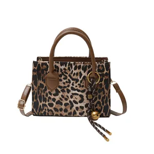 Fashionable leopard print tote bag with brown handles and adjustable shoulder strap