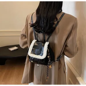 Detalle de una pequeña mochila chic de cuero negro y piel de oveja blanca en modelo